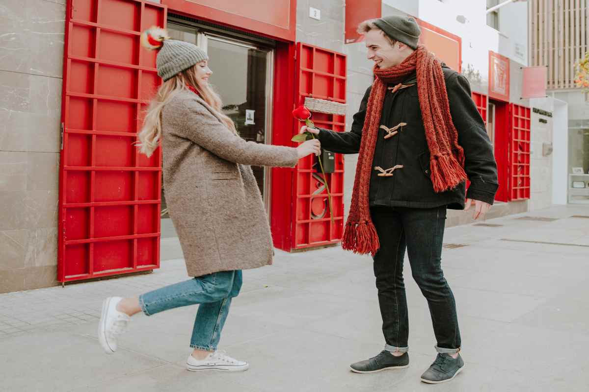 Happy couple holding house keys in front of sold property in the UK. 
